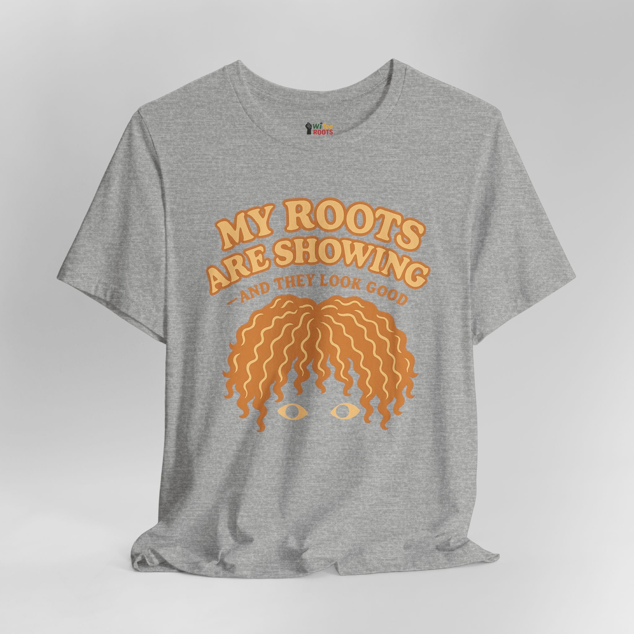 Gray t-shirt with orange graphic and text 'My roots are showing and they look good' on a light gray background