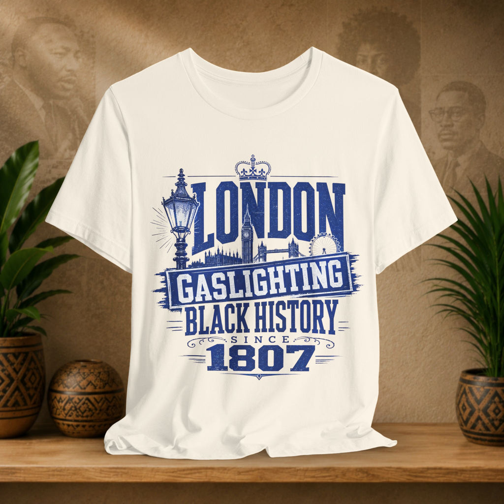 Beige t-shirt with 'London Gaslighting Black History Since 1807' design on a wooden surface with plants and a blurred background.