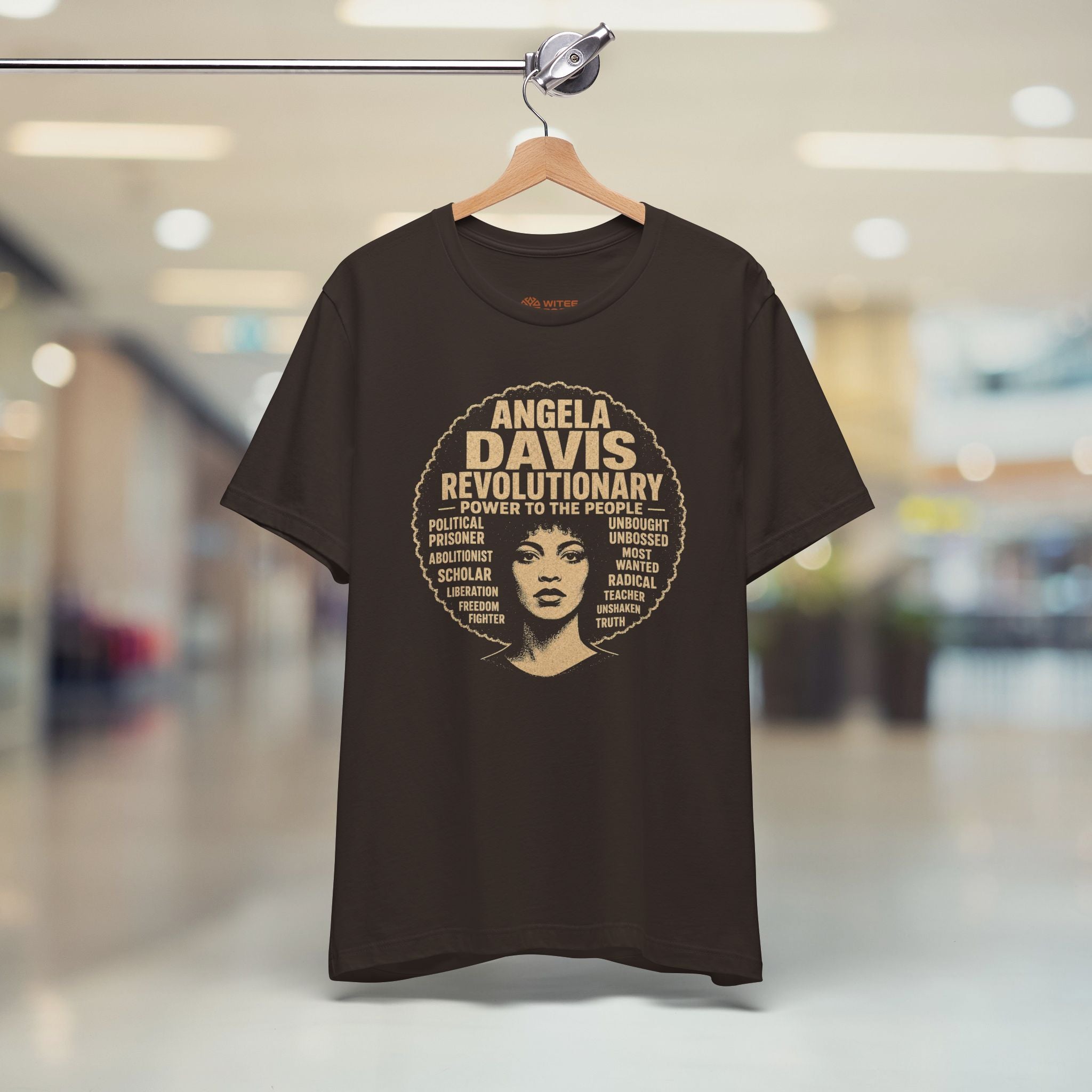 brown t-shirt with 'RESIST' text on a hanger in a store setting