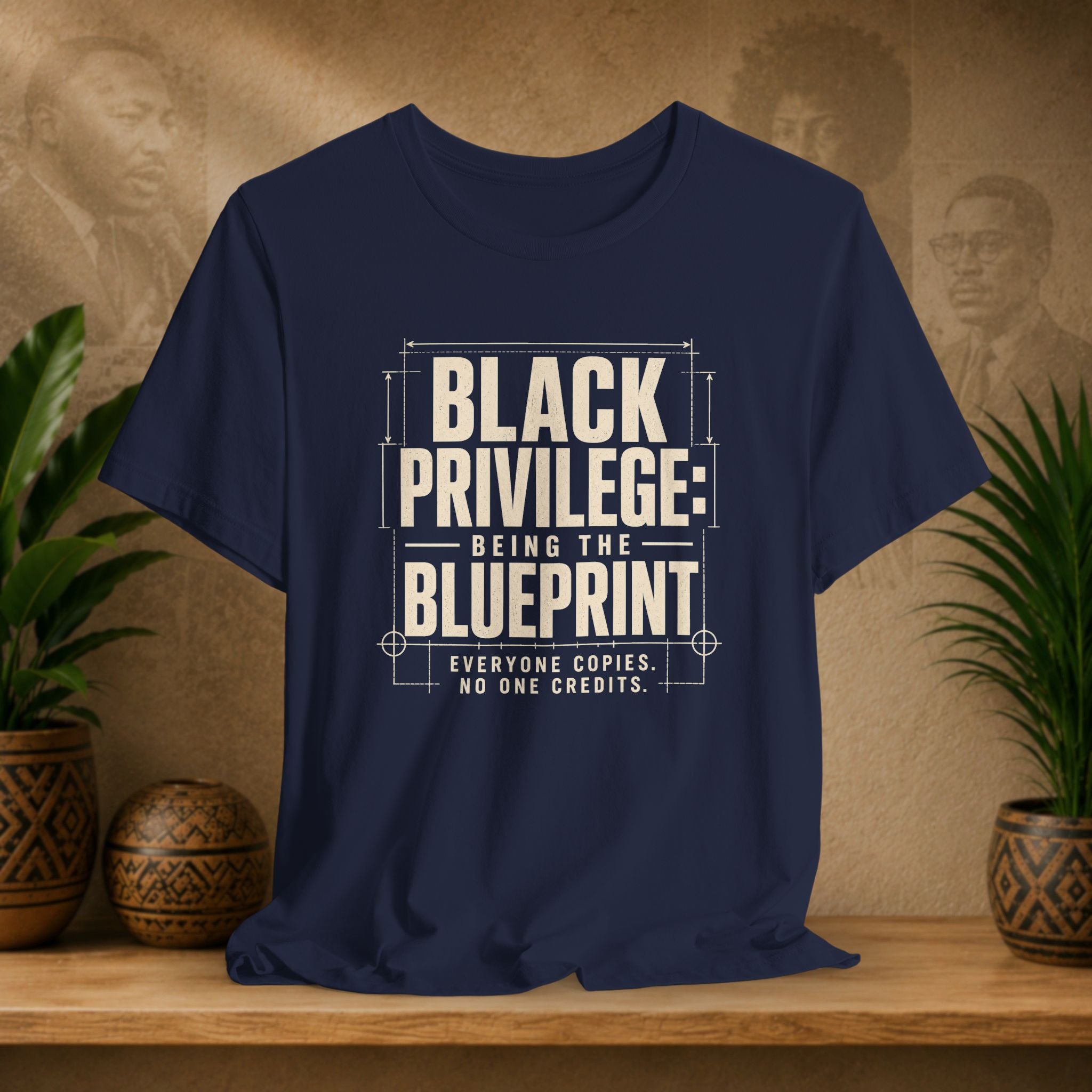 Navy blue t-shirt with white text on a wooden surface with plants and decorative items in the background
