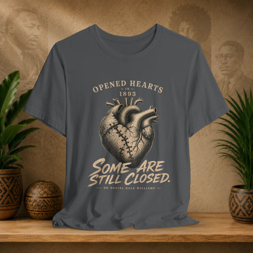 Gray t-shirt with heart design and text on a wooden surface with plants and decorative items.