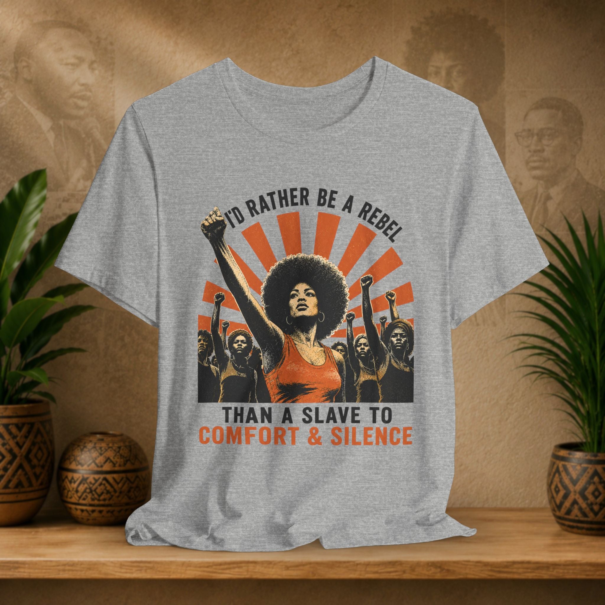 Gray t-shirt with graphic design of a woman raising a fist and text on a wooden surface with plants.