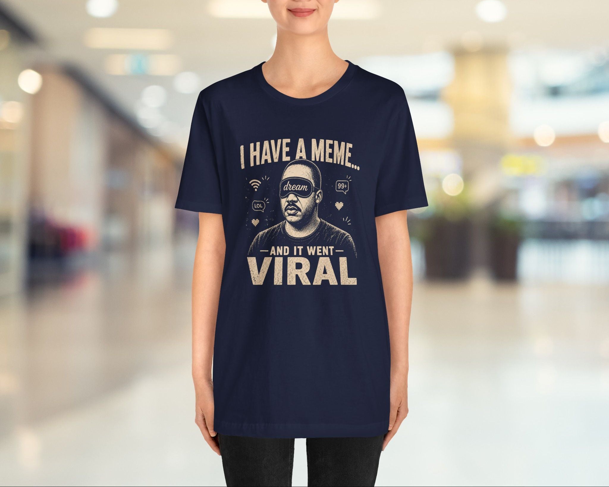 Person wearing a navy blue t-shirt with humorous text design in a blurred indoor setting