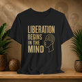 Black t-shirt with 'Liberation Begins in the Mind' text and a profile graphic on a wooden surface with decorative items.