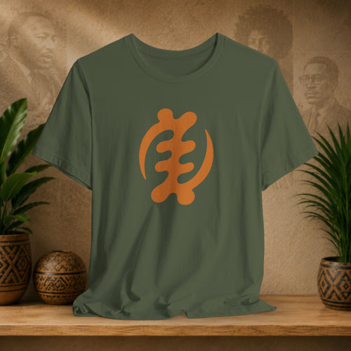 Green t-shirt with orange symbol on a wooden surface with plants and a textured wall background