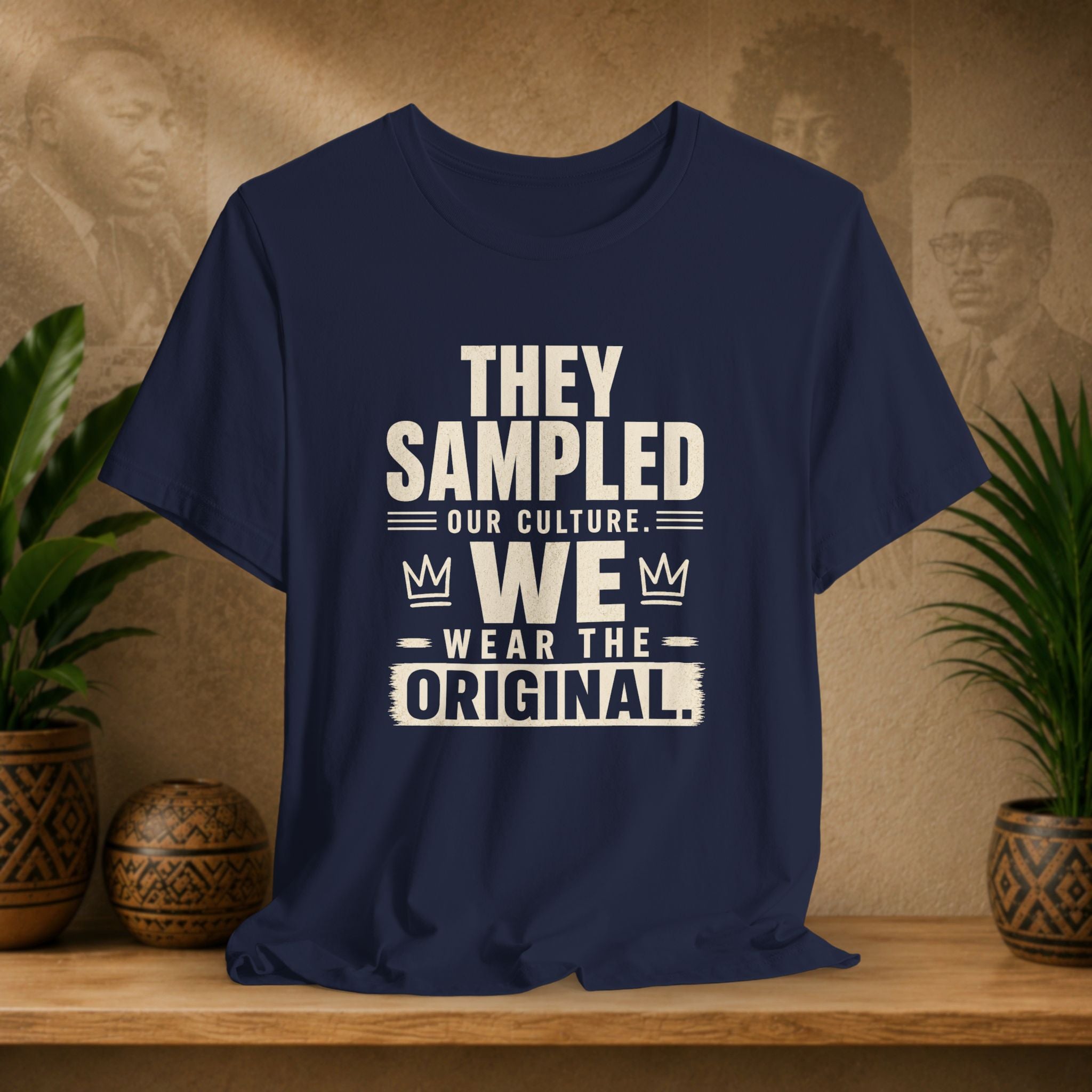 Navy blue t-shirt with white text on a wooden surface with plants and a textured wall background