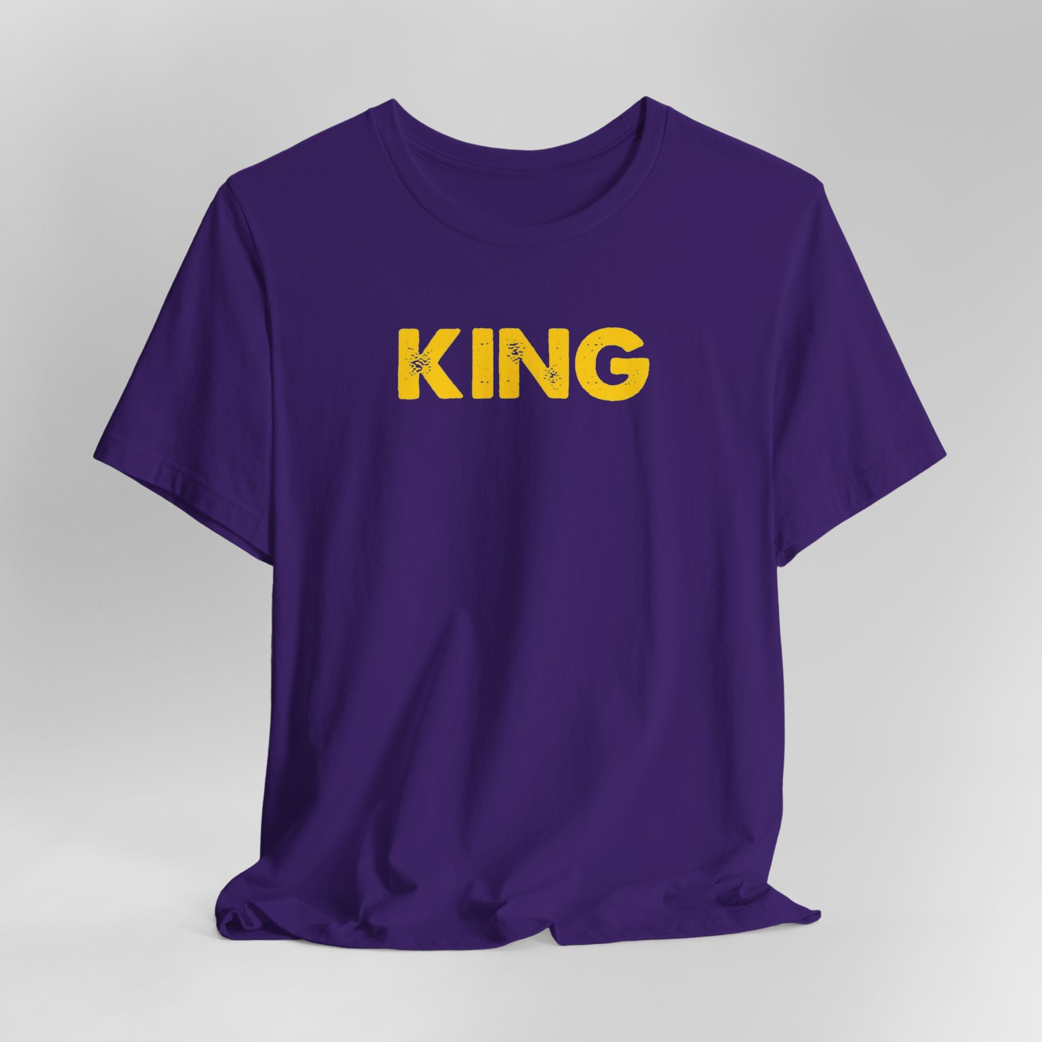 Purple t-shirt with 'KING' printed in yellow on a gray background