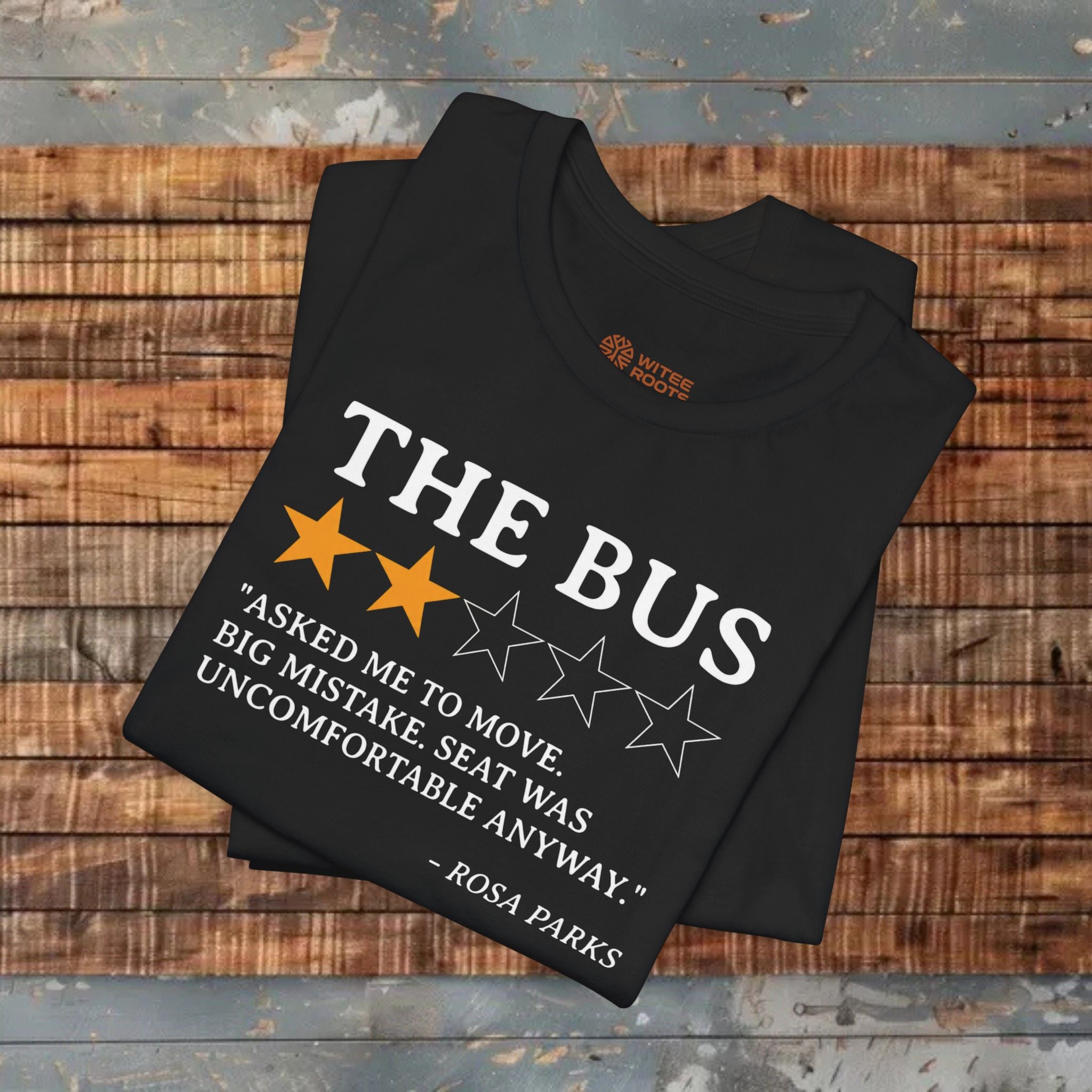 Black t-shirt with 'The Bus' graphic and quote on a wooden surface