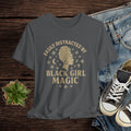 Gray t-shirt with 'Easily Distracted by Black Girl Magic' design on a wooden surface with jeans and sneakers.