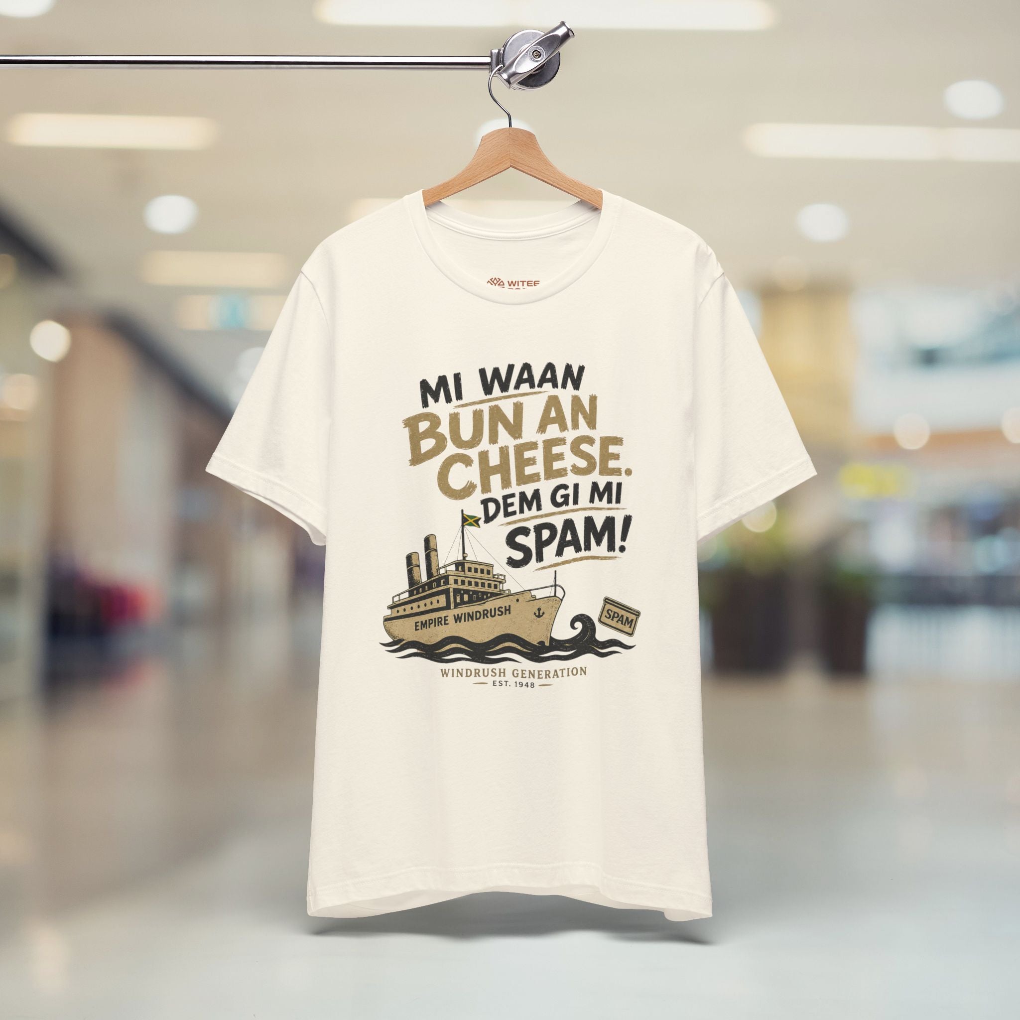 Beige t-shirt with humorous graphic and text on a hanger in a store setting
