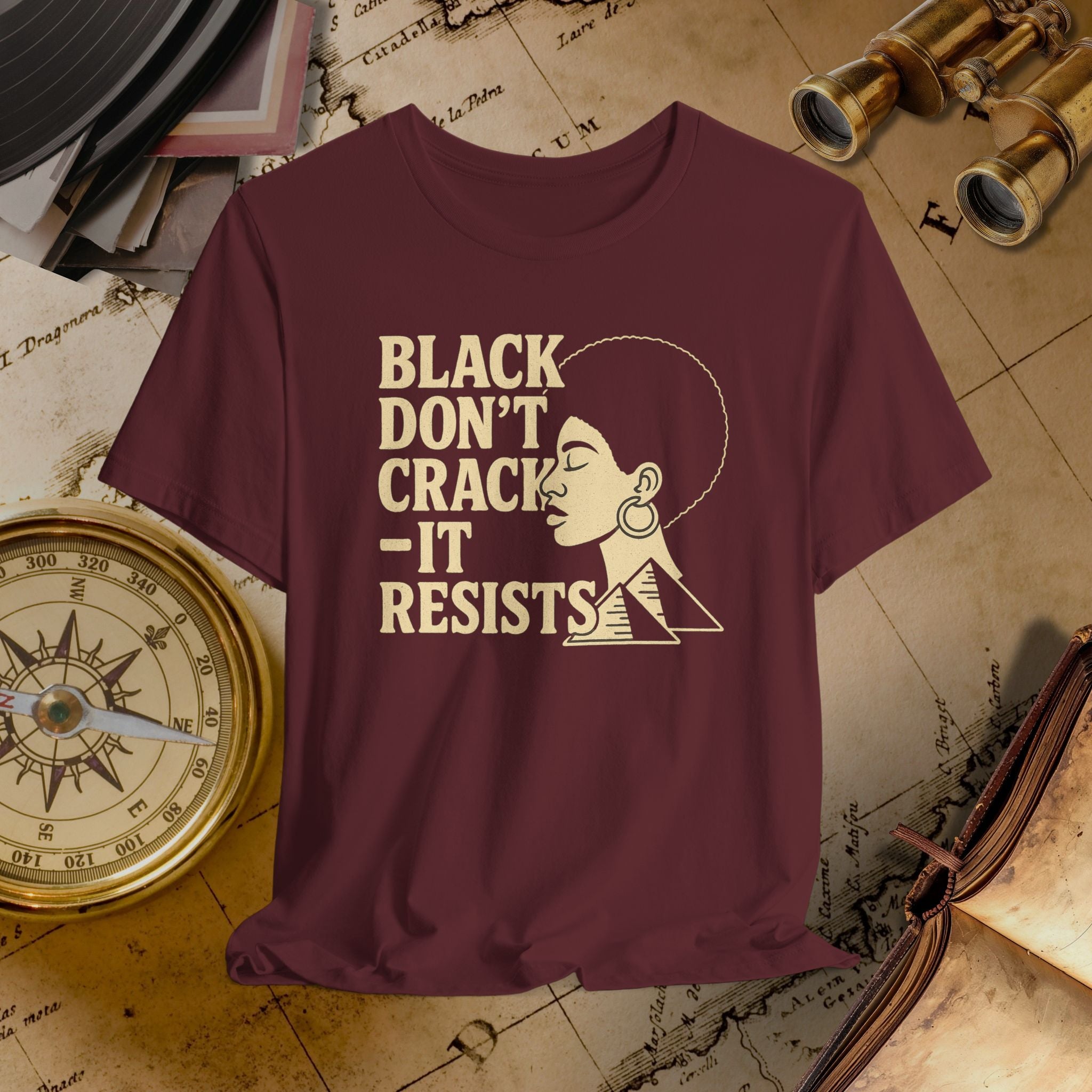 Maroon t-shirt with gold text and illustration of a woman, placed on an old map background. 