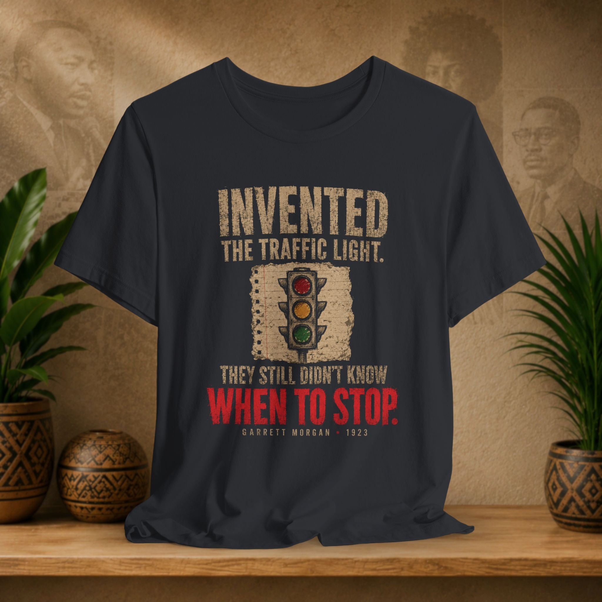 Black t-shirt with traffic light graphic and text on a wooden surface with plants and decorative items.