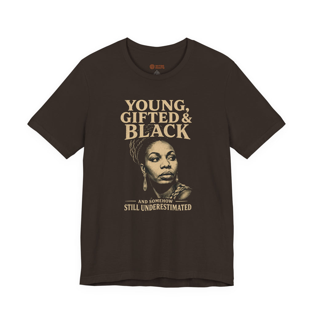 A dark brown short-sleeve graphic t-shirt featuring a portrait of Oprah Winfrey and the text 'YOUNG, GIFTED & BLACK' and 'AND SOMEHOW STILL UNDERESTIMATED' in a tan/beige color, displayed against a solid white background.