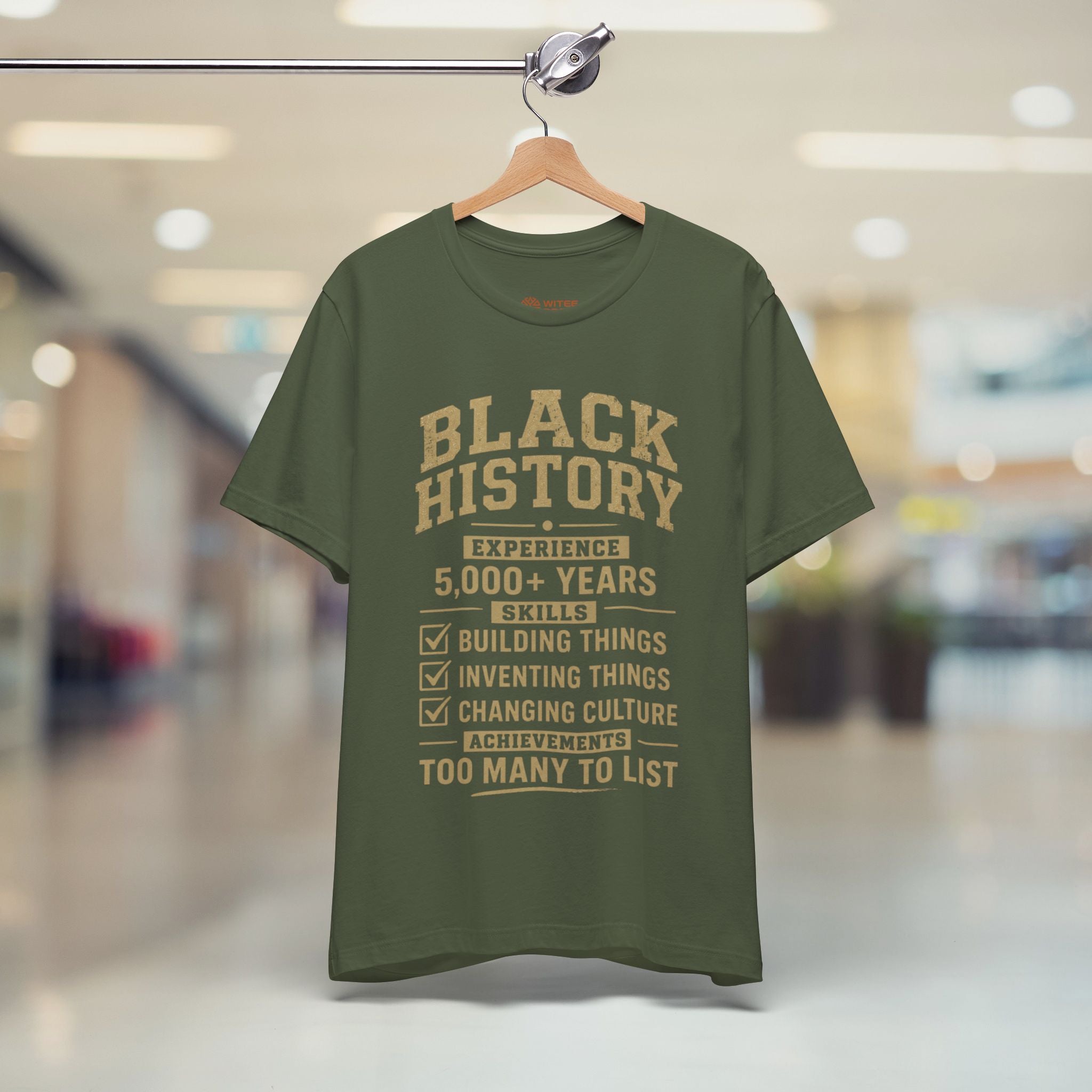 Green t-shirt with 'Black History' text on a hanger in a store setting