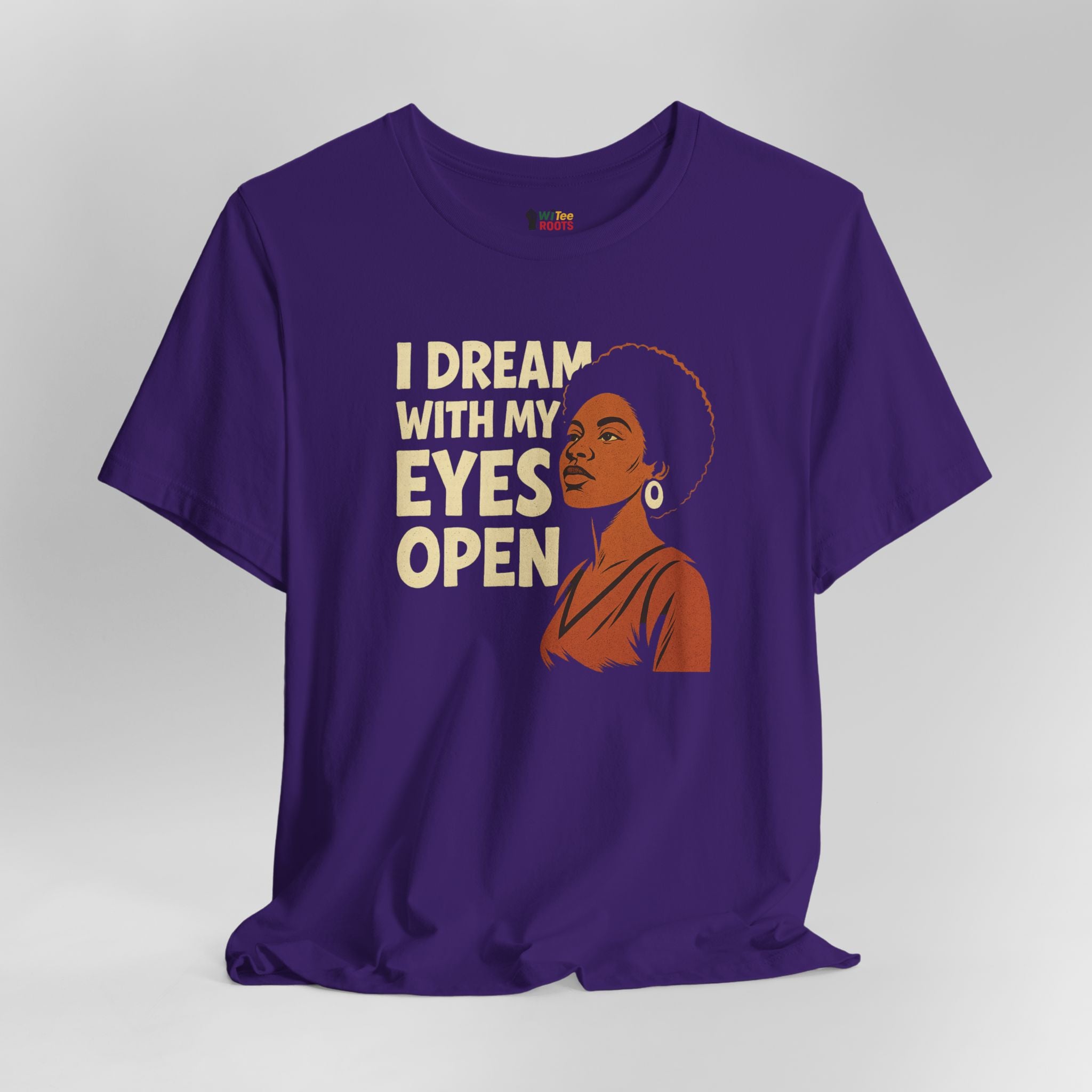 Purple t-shirt with a graphic of a woman and text 'I Dream with My Eyes Open' on a gray background