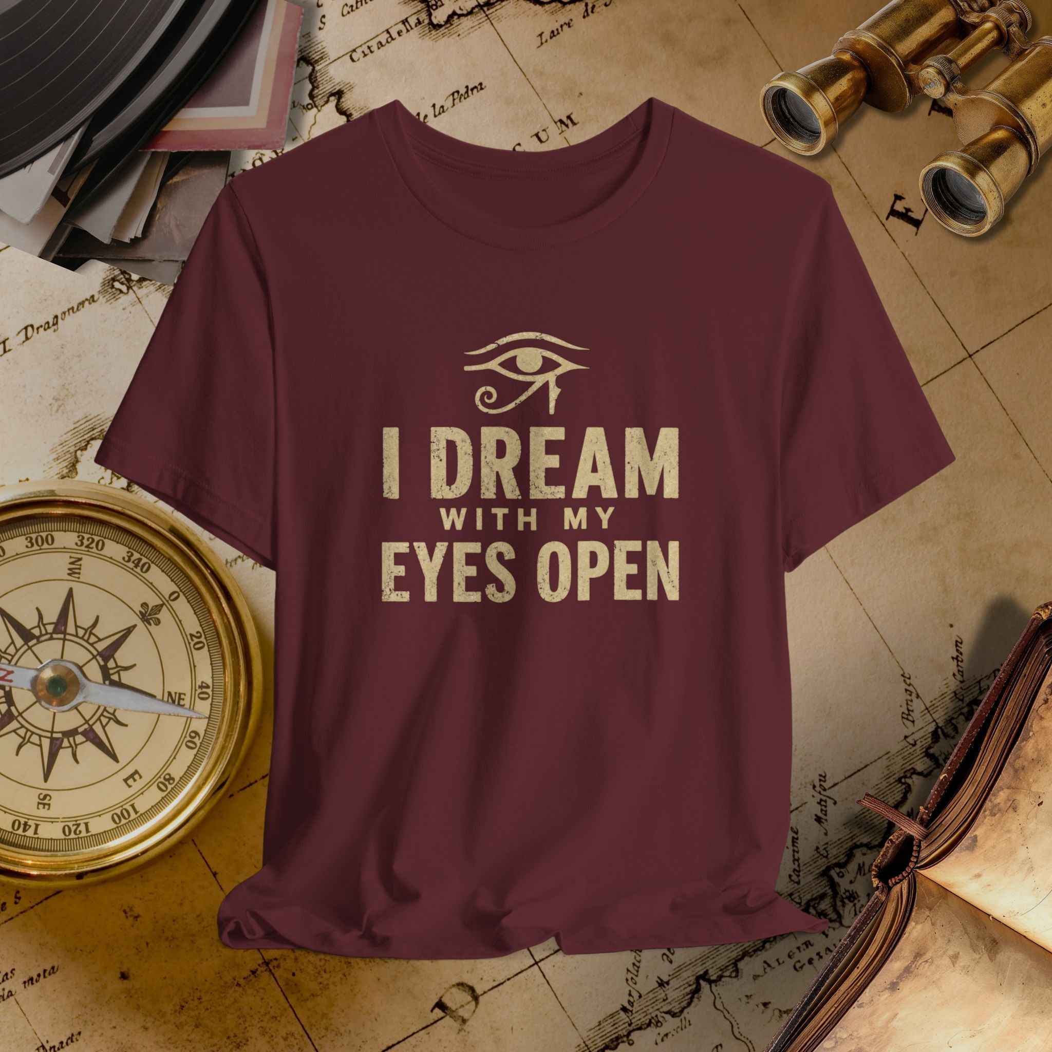 Maroon t-shirt with 'I Dream with My Eyes Open' text and eye symbol on a vintage map background.