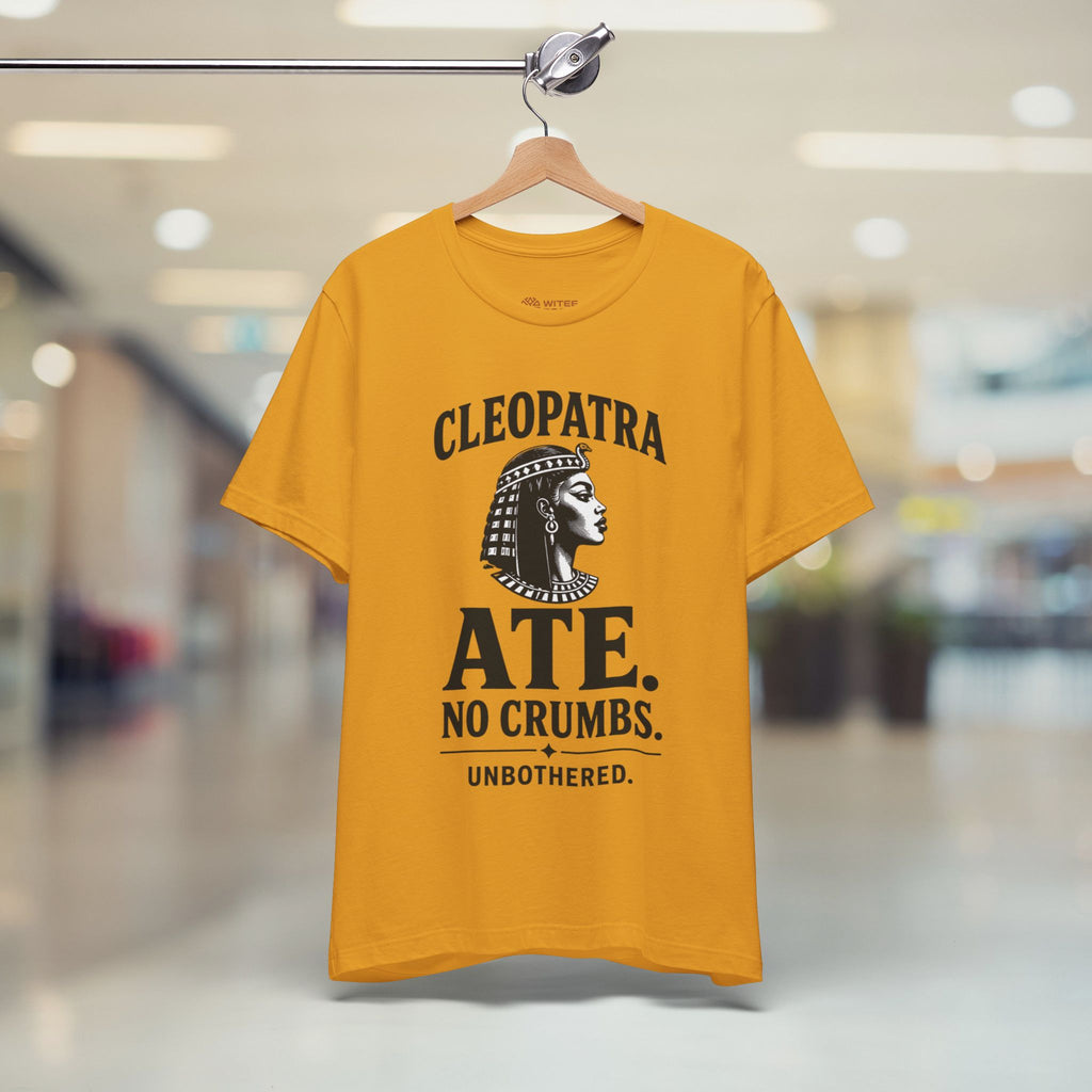 Yellow t-shirt with Cleopatra graphic and text on a hanger in a store.
