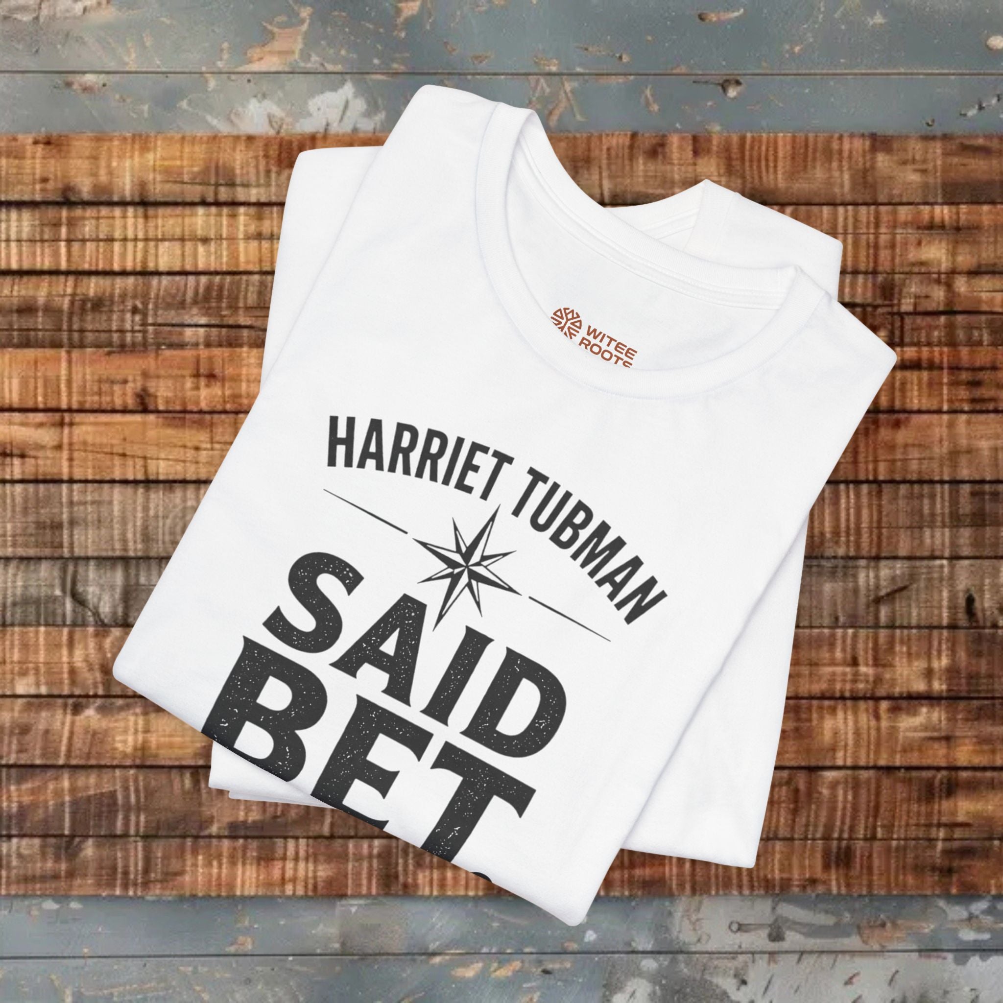 White t-shirt with 'Harriet Tubman Said Bet' text on a wooden surface
