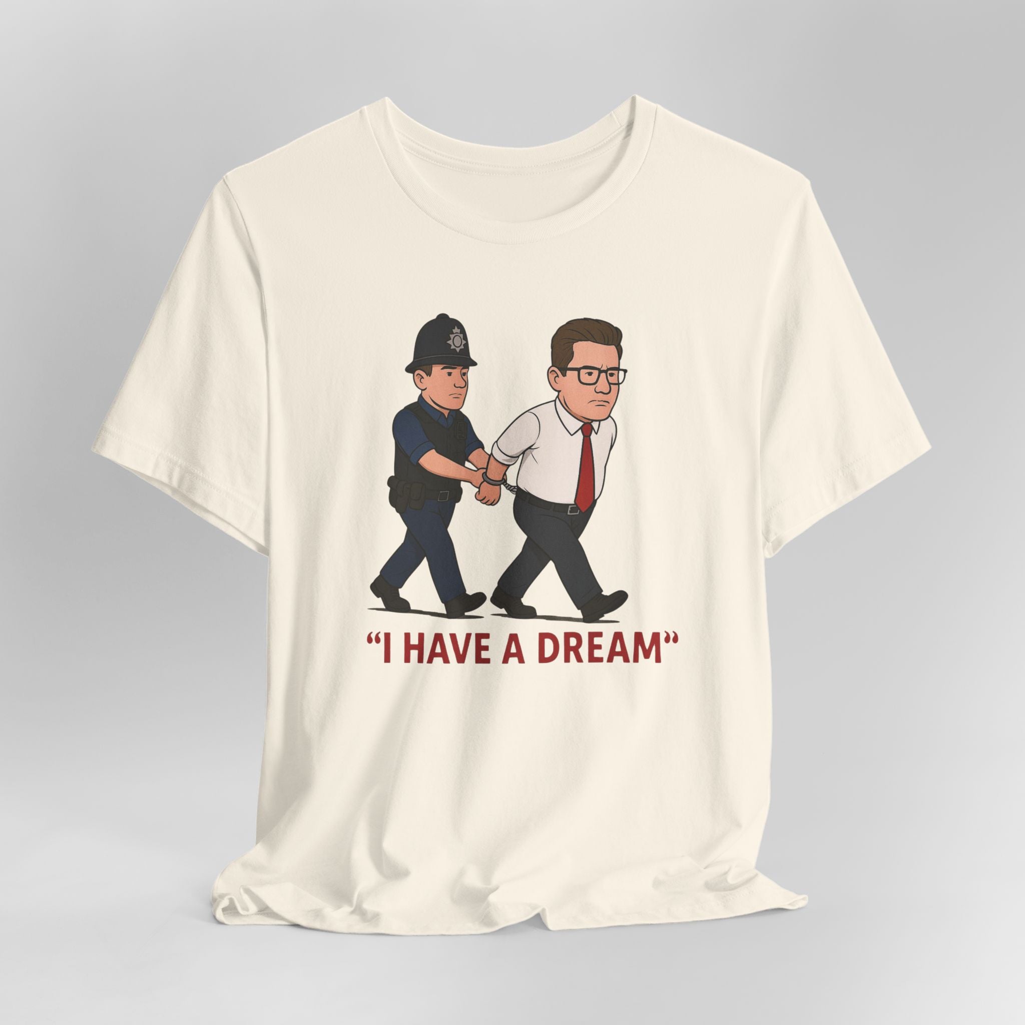 Cream t-shirt with graphic of a police officer and a man in a suit, with 'I HAVE A DREAM' text, on a gray background.