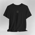 Black t-shirt with a small logo on a light gray background