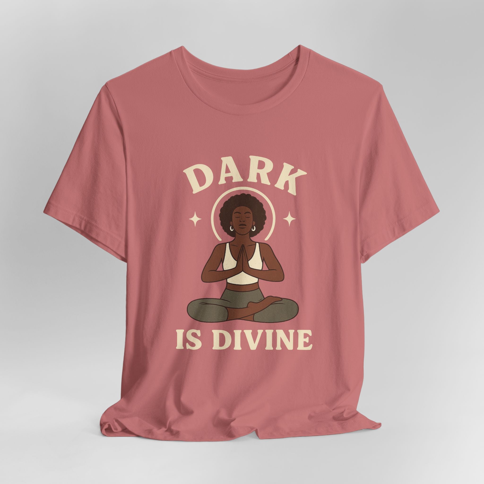 Mauve t-shirt with a graphic of a woman in a meditative pose and 'Dark is Divine' text on a gray background