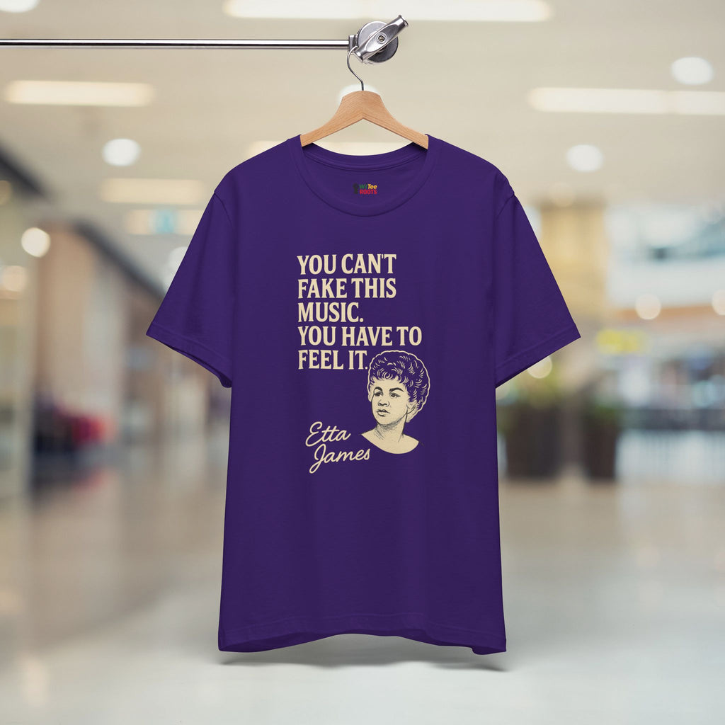 Purple t-shirt with text and graphic of Etta James on a hanger in a store.