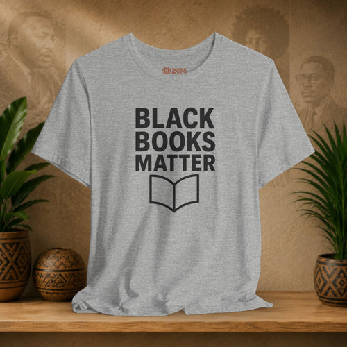 Gray t-shirt with 'Black Books Matter' text on a wooden shelf with plants and a decorative item.