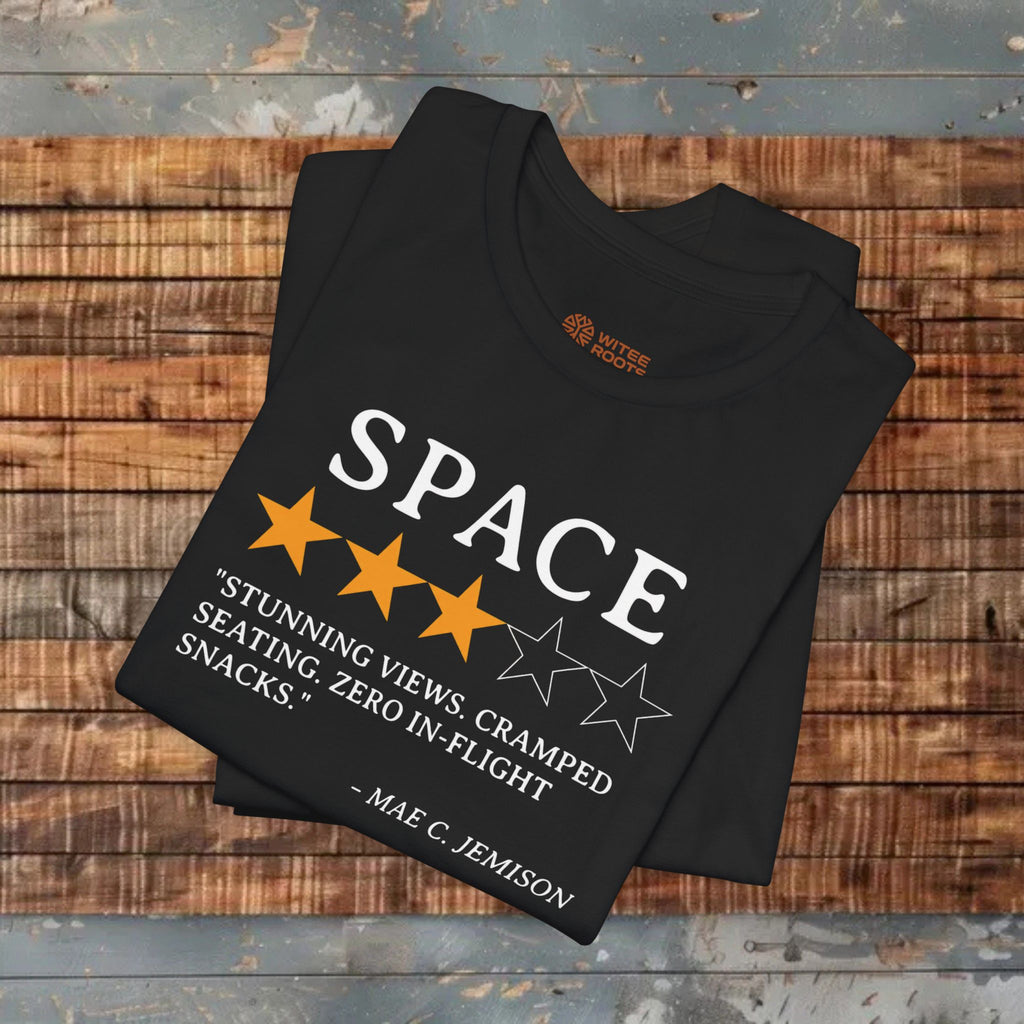 Folded black t-shirt with space-themed design on a wooden surface