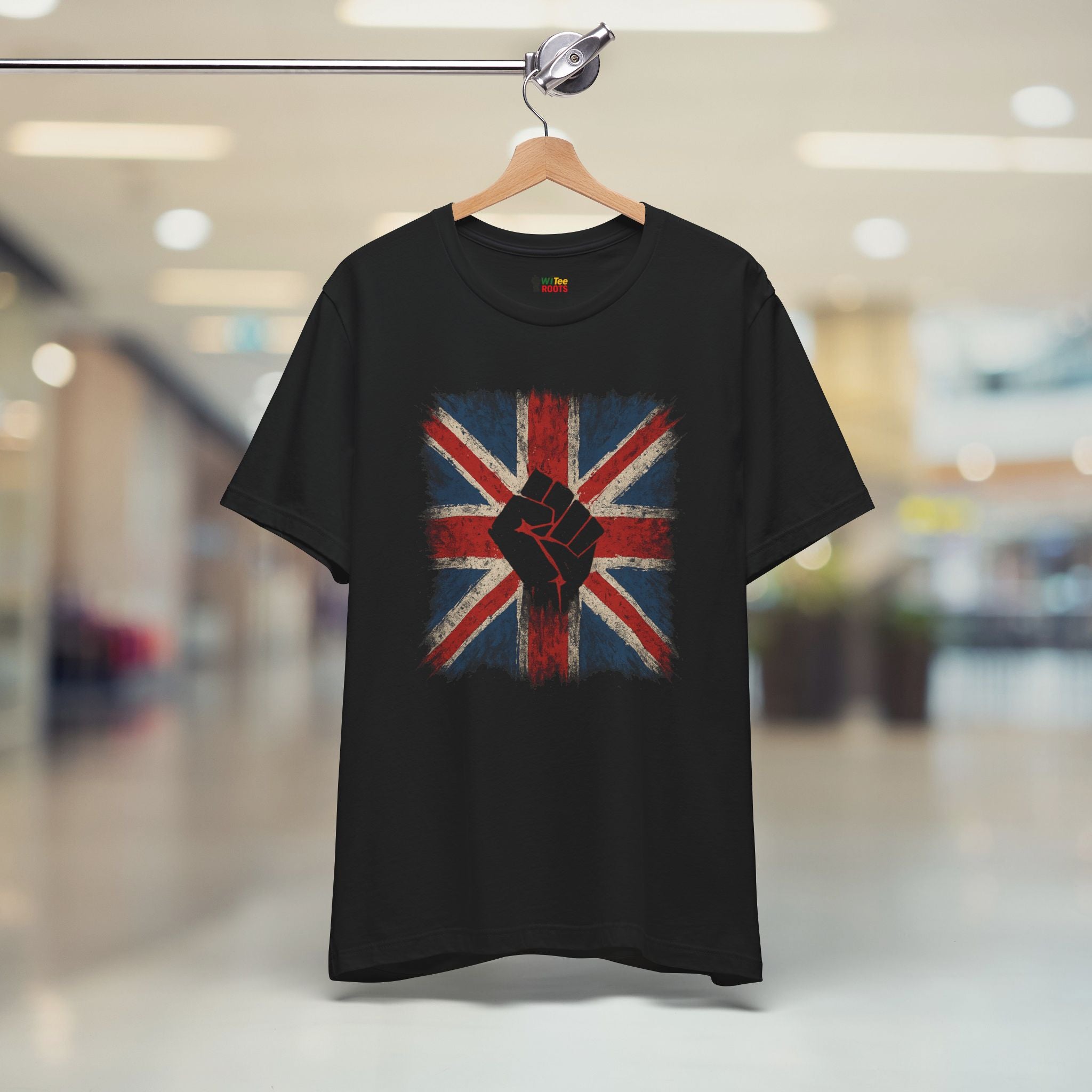 Black t-shirt with a Union Jack design featuring a raised fist, hanging on a blurred indoor background.