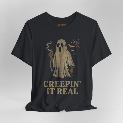 A black short-sleeve t-shirt with a distressed beige graphic of a smoking ghost and the text 'CREEPIN' IT REAL' on the front, displayed against a neutral gray background.