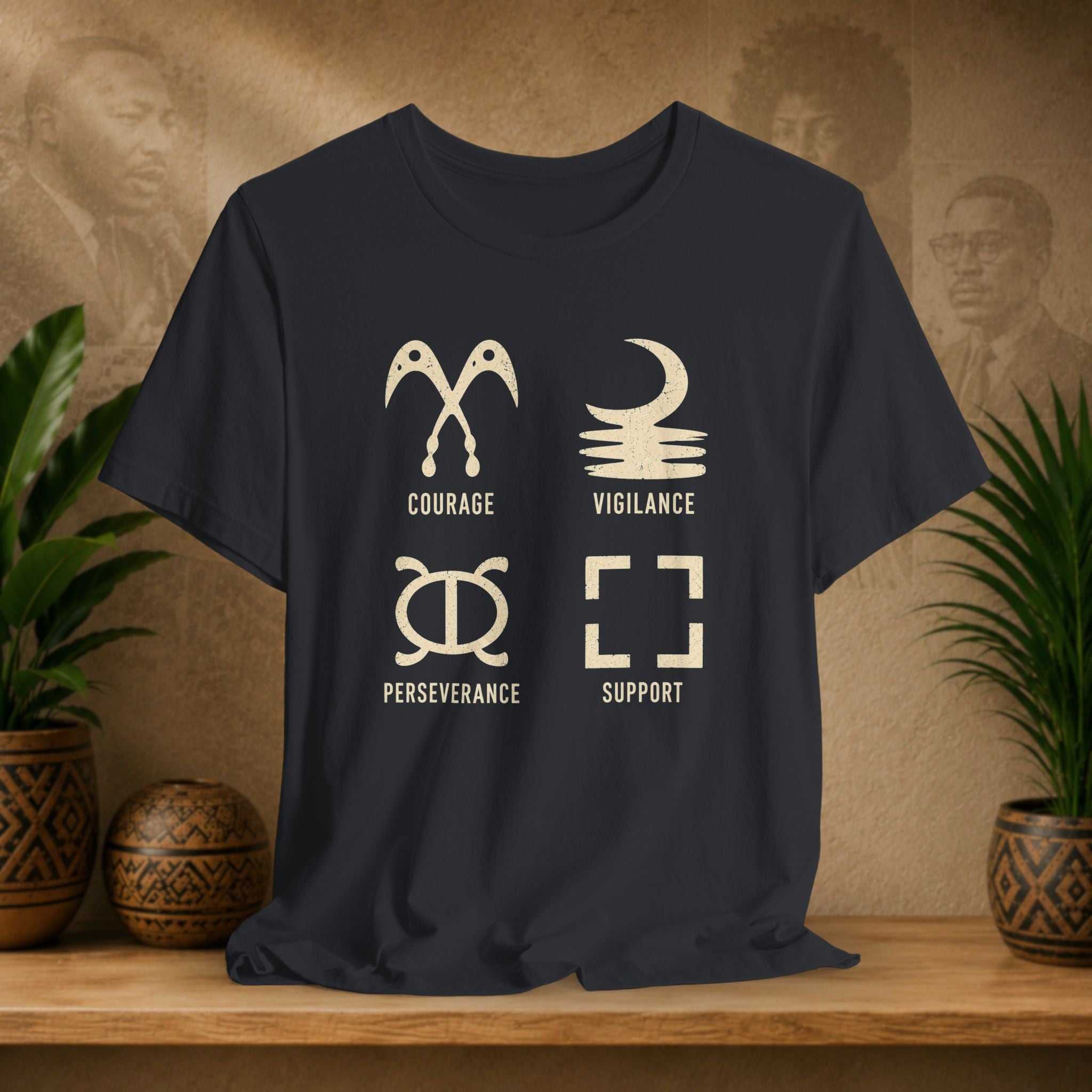 Black t-shirt with white symbols and text on a wooden surface with decorative plants and background.