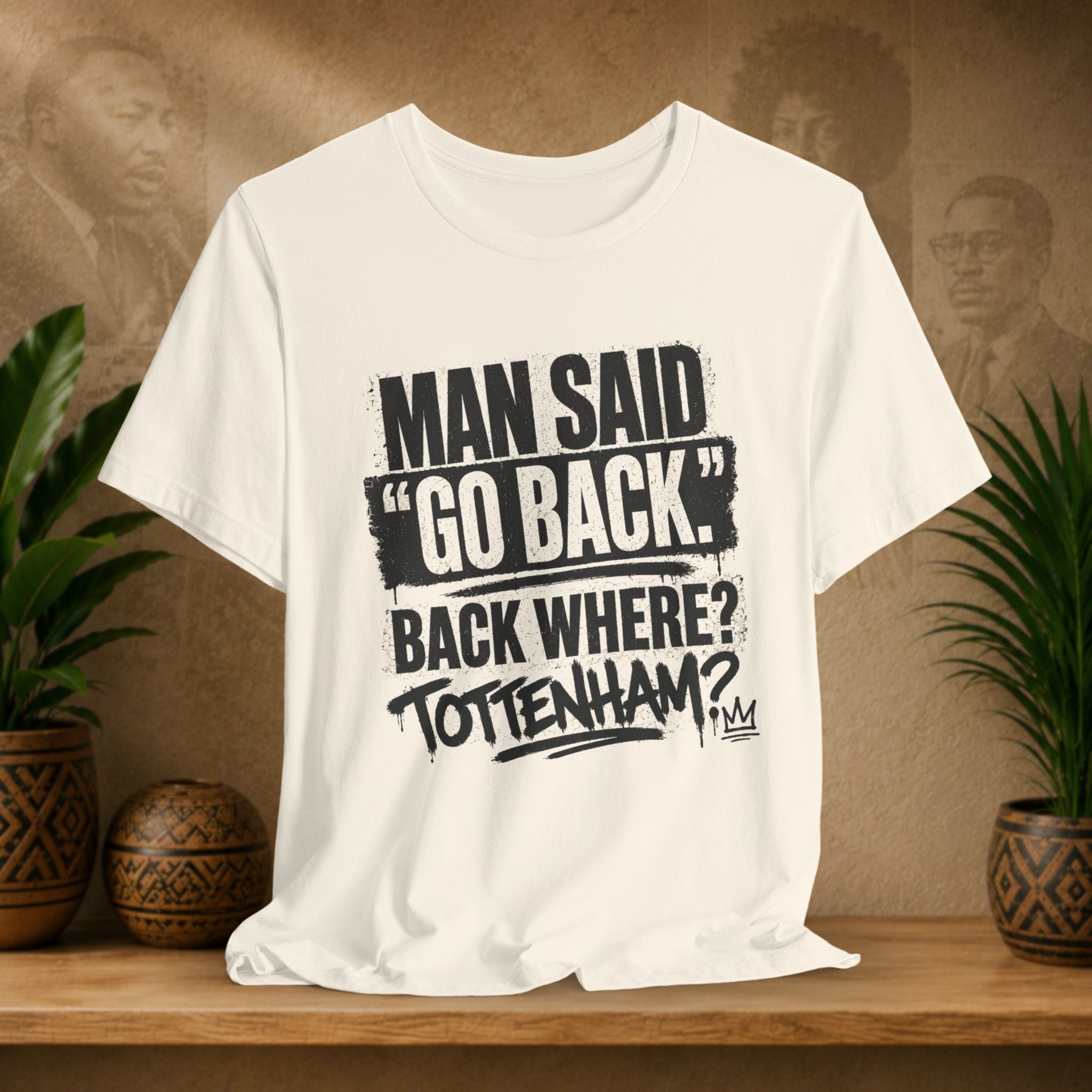 Beige t-shirt with black text on a wooden surface with plants and a brown background
