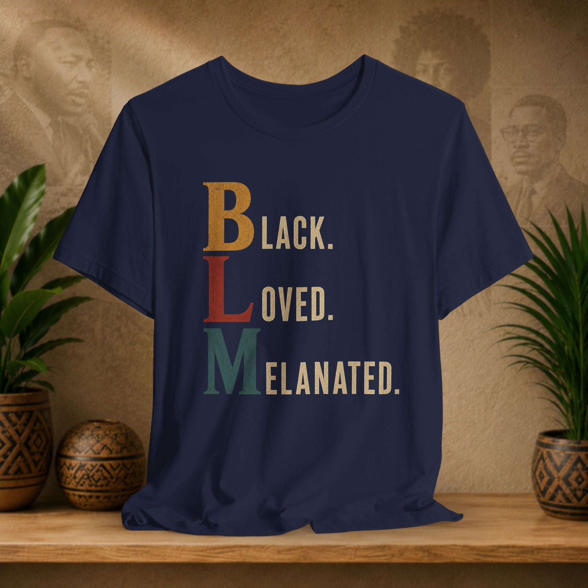 A navy blue graphic t-shirt displayed on a wooden shelf, featuring the text 'Black. LOVED.