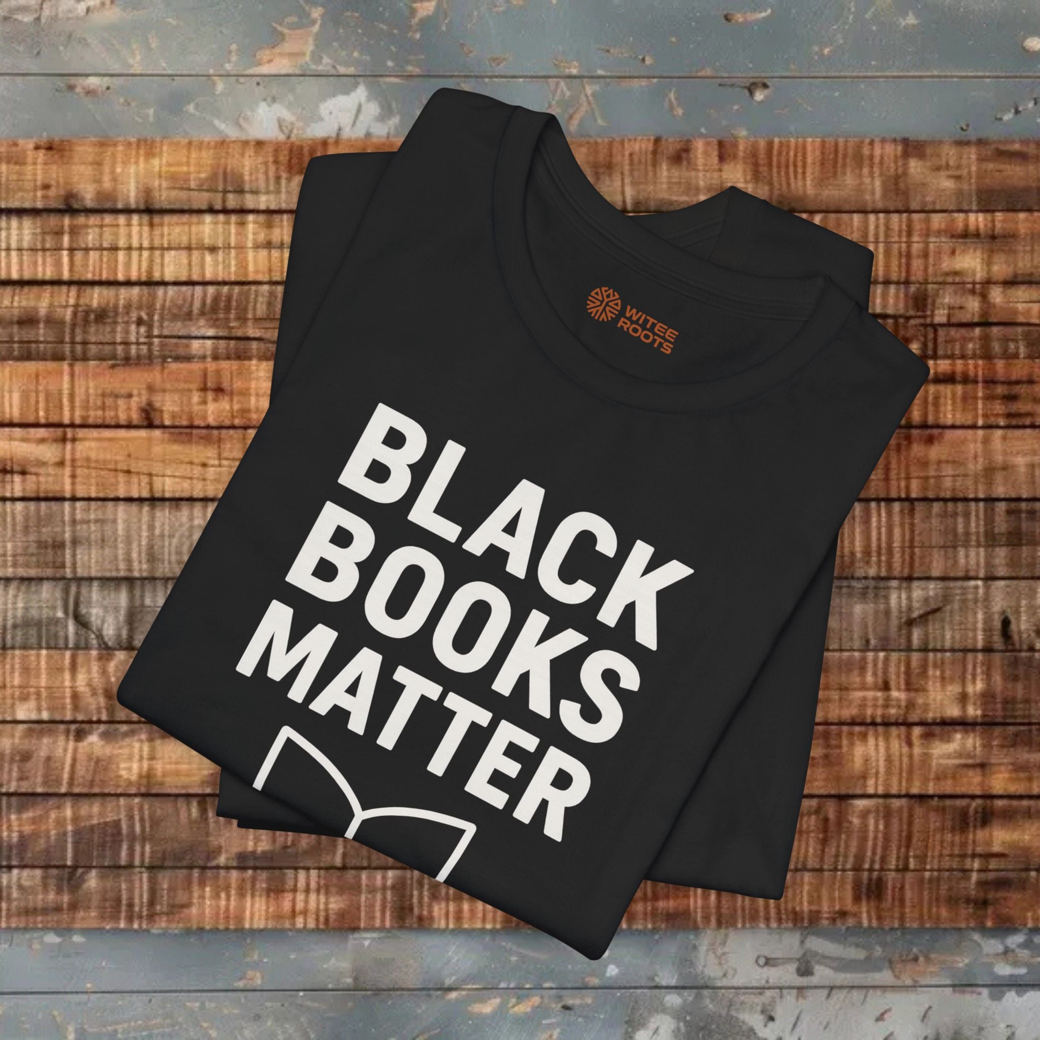 Black t-shirt with 'BLACK BOOKS MATTER' text on a wooden surface
