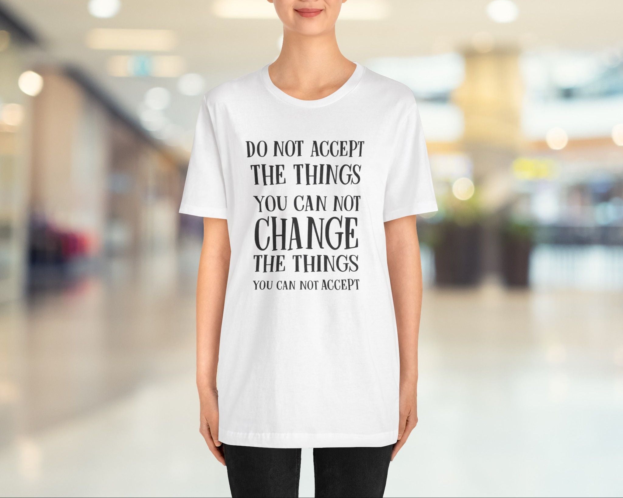 Person wearing a white t-shirt with a motivational quote in a blurred indoor setting