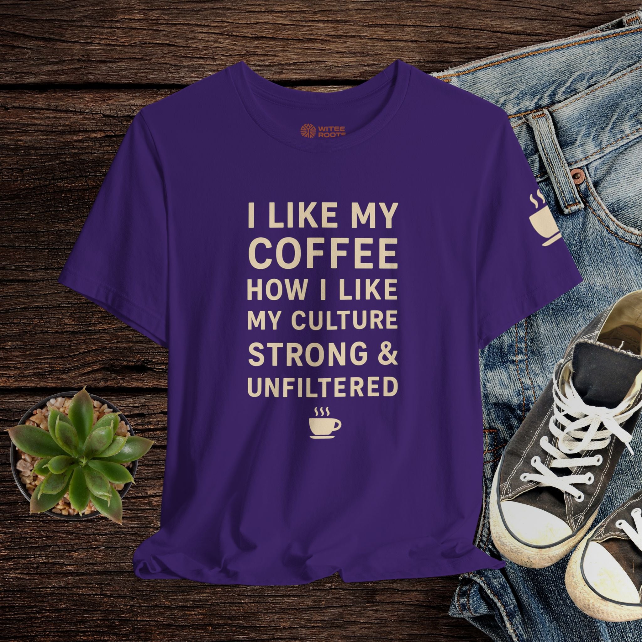 Purple t-shirt with text on a wooden surface with jeans and sneakers.