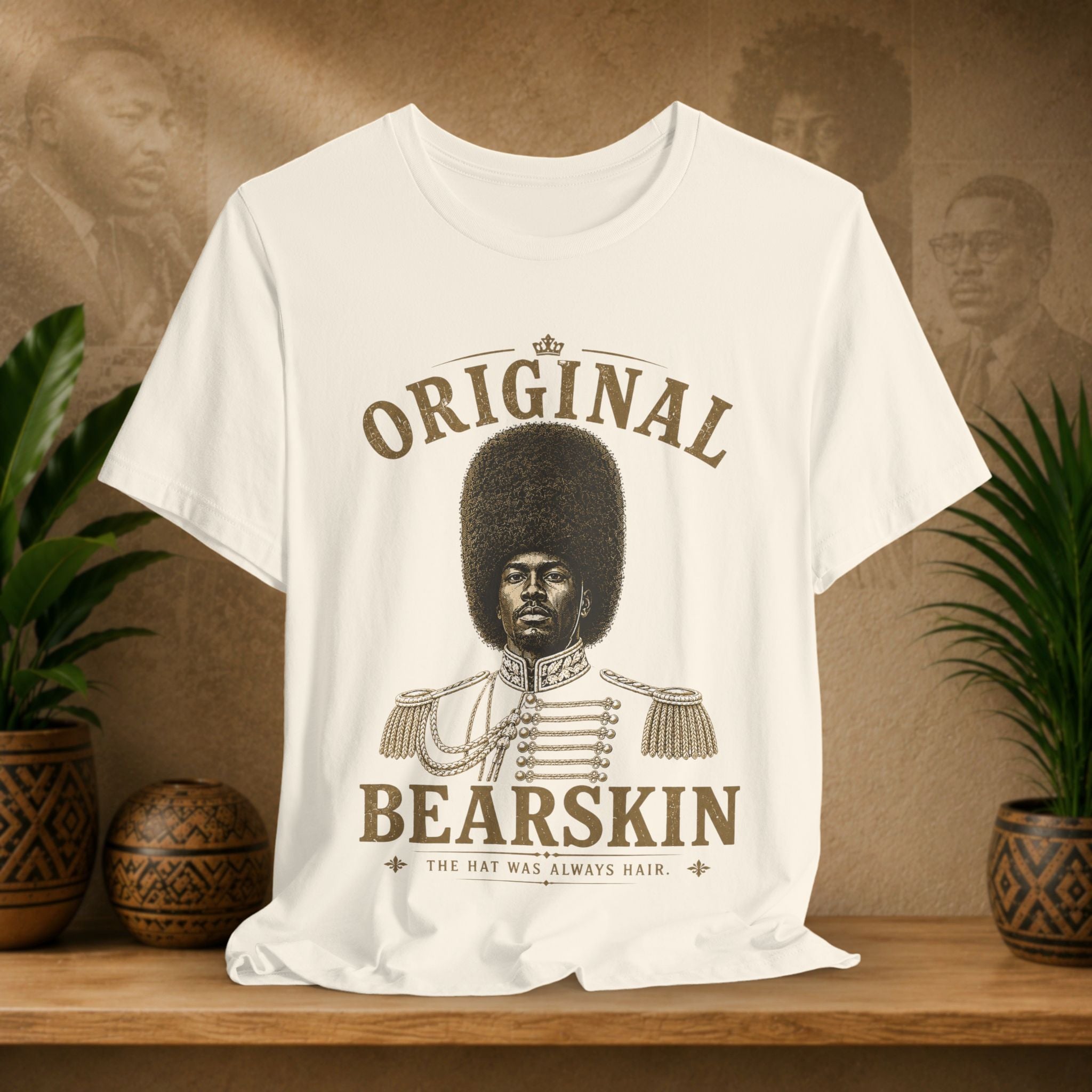 Beige t-shirt with 'Original Bearskin' design on a wooden surface with plants and a textured wall in the background.