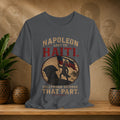 Gray t-shirt with historical graphic and text on a wooden shelf with plants and decorative items.