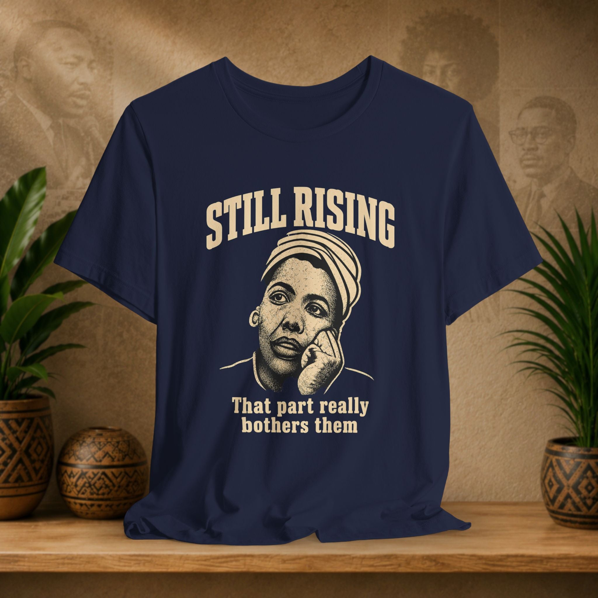 Navy t-shirt with graphic and text on a wooden surface with plants and a textured wall background