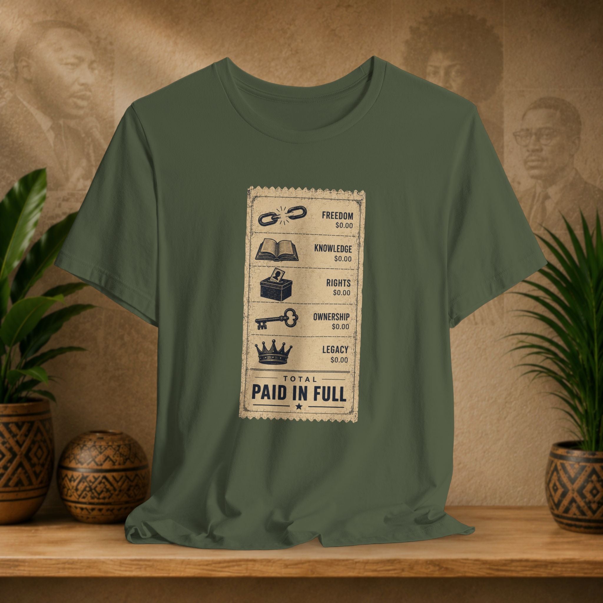 Green t-shirt with a graphic design on a wooden surface with plants and a textured wall in the background