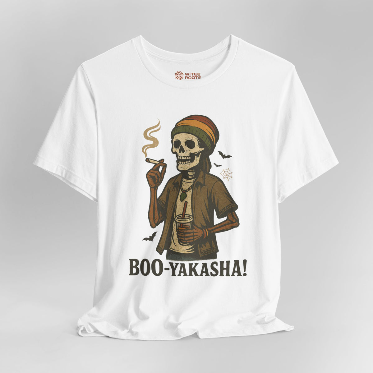 A white short-sleeve t-shirt with a graphic of a skeleton wearing a Rasta hat and holding a cigar and a drink, with the text 'BOO-YAKASHA!' printed below. The shirt is shown on a neutral gray background.