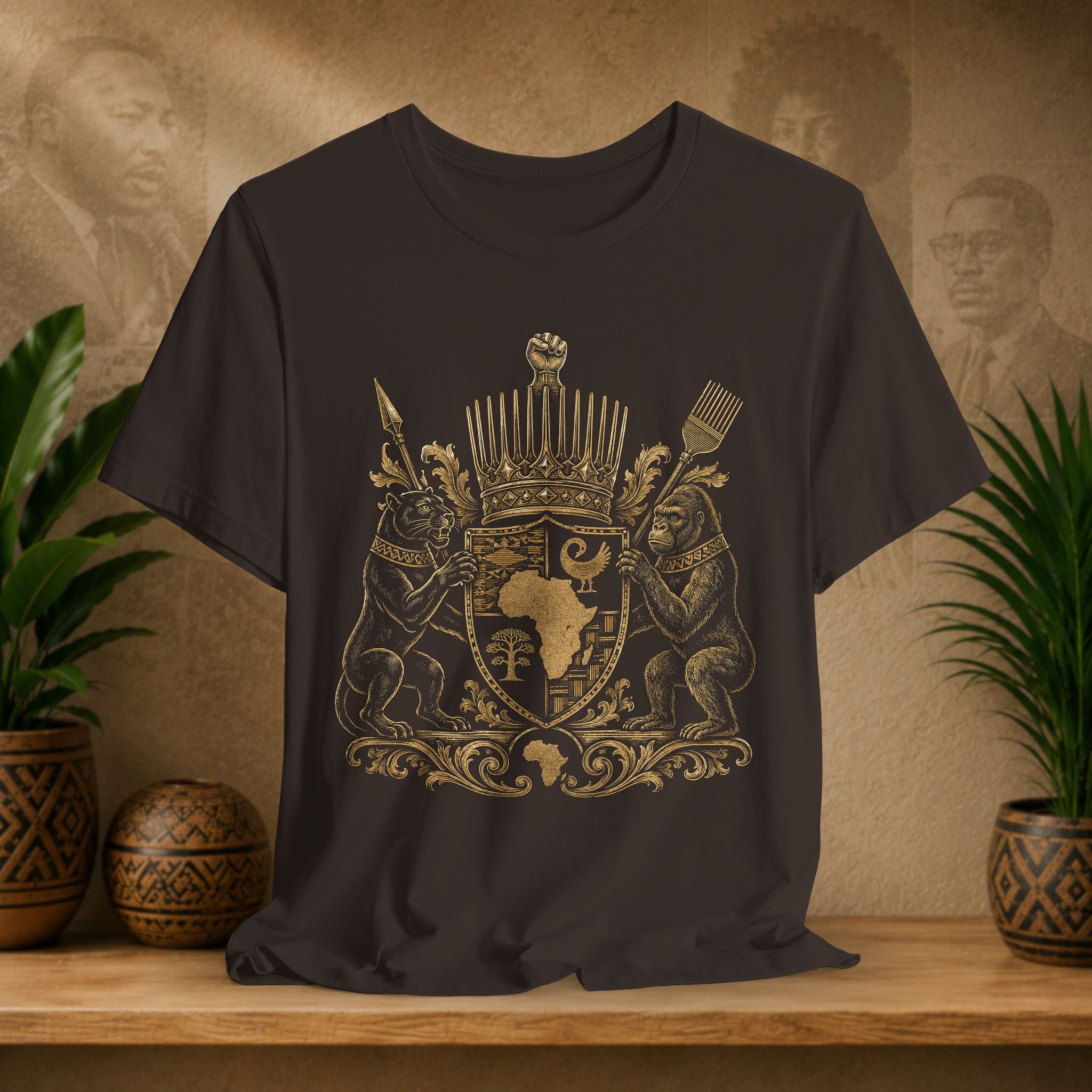 Brown t-shirt with gold emblem featuring African design on a wooden surface with plants and decorative items.