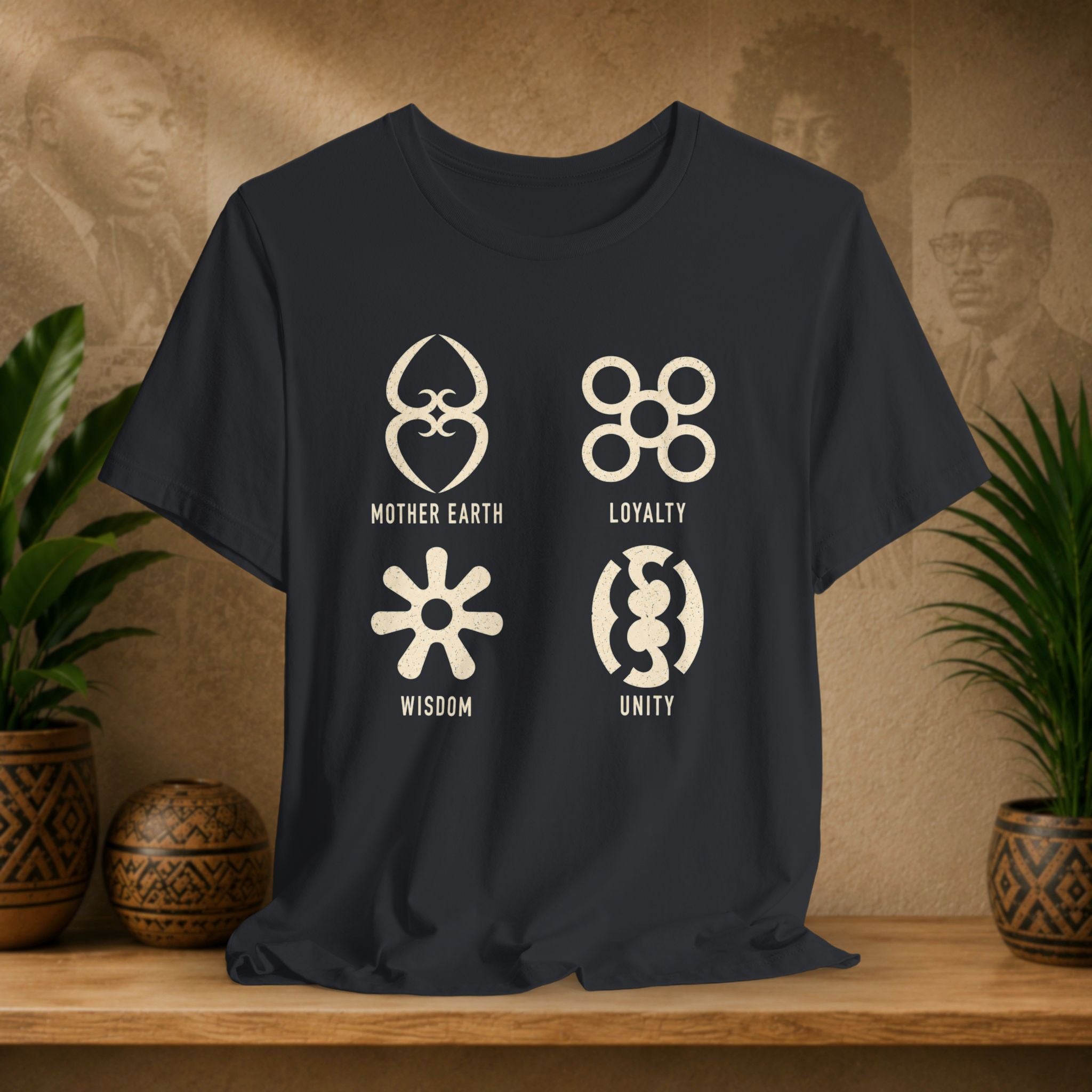Black t-shirt with symbols and text on a wooden surface with plants and decorative items.