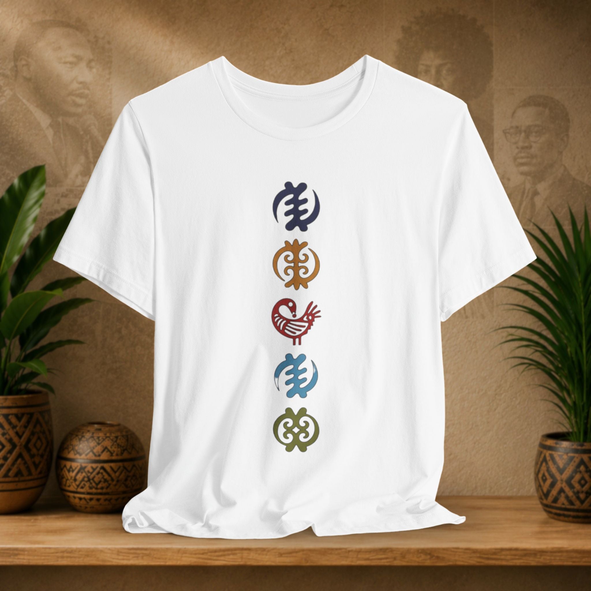 White t-shirt with colorful symbols on a wooden shelf with plants and a textured wall background
