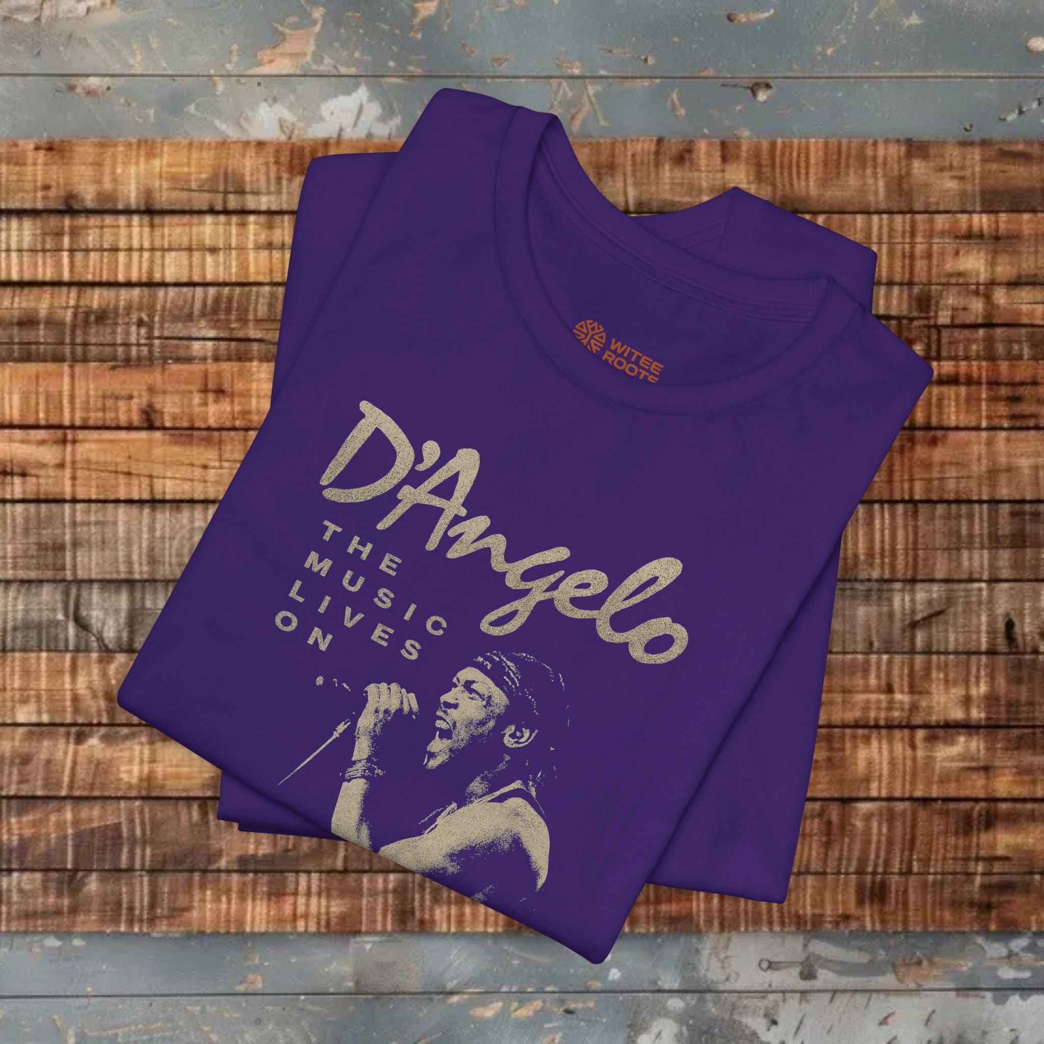 Folded purple t-shirt with 'D'Angelo' text and graphic on a wooden surface