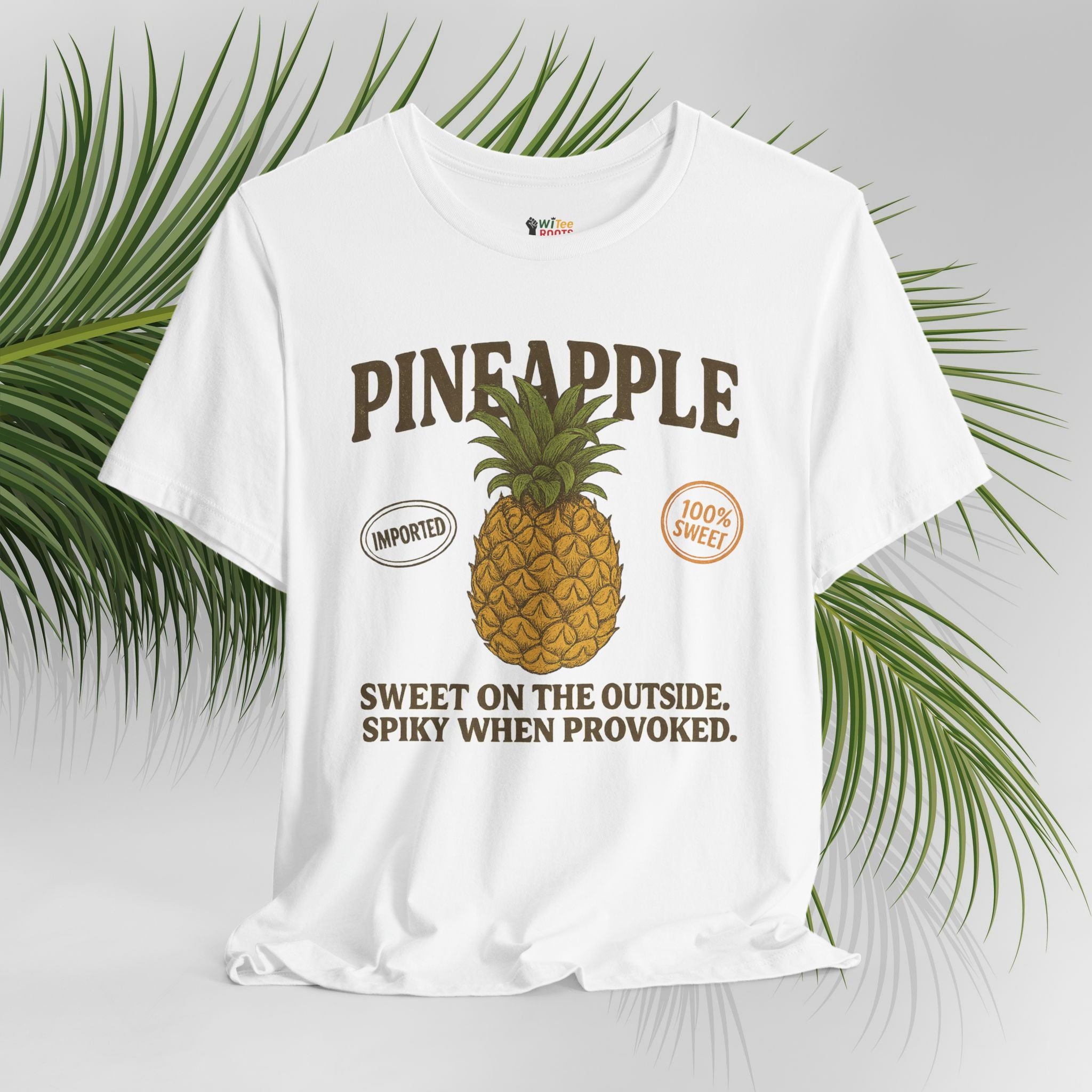 White t-shirt with pineapple graphic and text on a light gray background with green leaves.