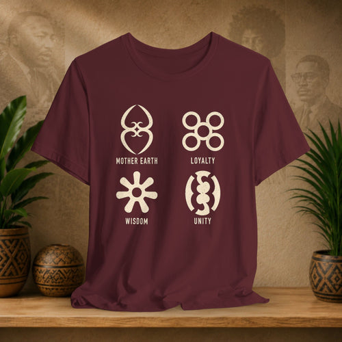 Maroon t-shirt with symbols and text on a wooden surface with plants and a textured wall background