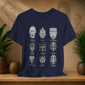 Navy blue t-shirt with white tribal mask designs on a wooden surface with plants and decorative items.