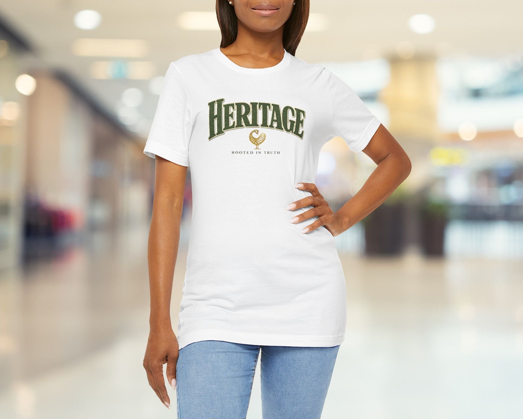 Woman wearing a white t-shirt with 'HERITAGE' printed on it in a blurred indoor setting