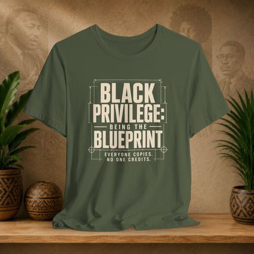 Green t-shirt with 'Black Privilege' text on a wooden surface with plants and a textured wall background
